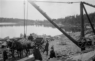Den här bilden visar det Schannongska stenbrottet vid Källsåker i Törnsfalls socken. Det är söndag i början av seklet och ägarfamiljen har gjort en utflykt till platsen. På en sten i förgrunden har man dukat fram spetsglas för lilla nubben och tilltugg i påse och öl att skölja ner med. Källa: Västervik 1900 till 1930 av Sven Kjällgren